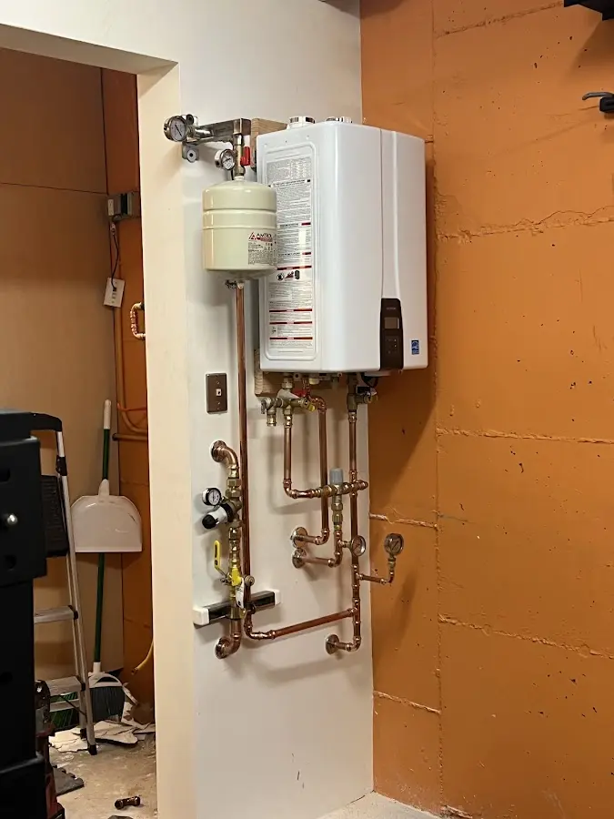 Plumbing technician inspecting water heater connections in North Adams